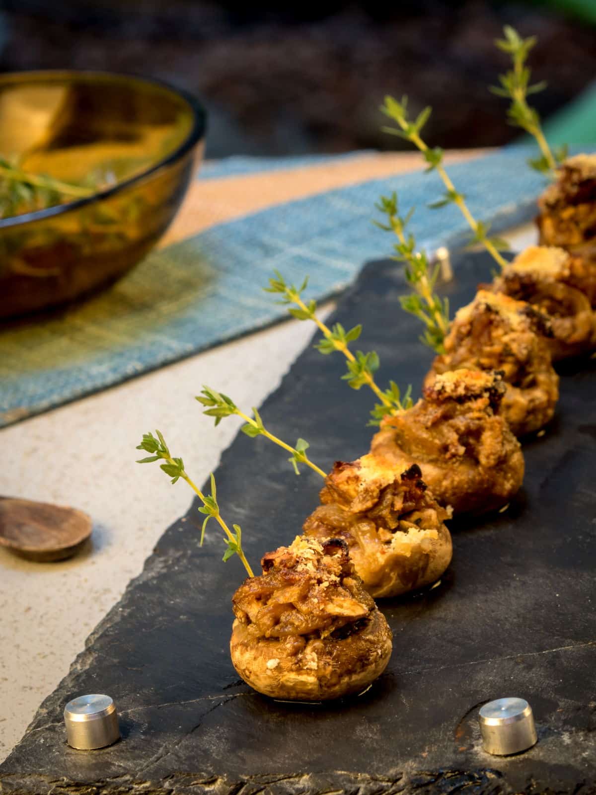 Stuffed button mushrooms arranged on black serving board.