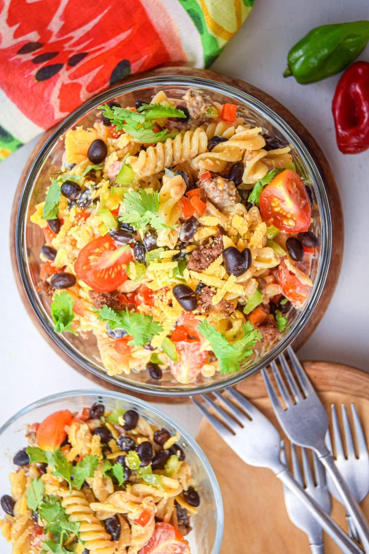 Taco pasta salad in clear bowls with forks on the side.