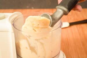 Scooping banana ice cream out of food processor.