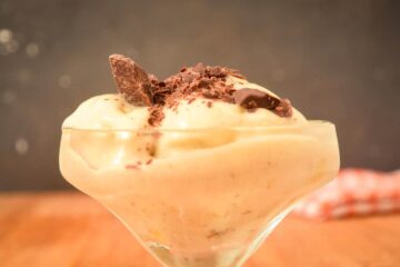 Vegan banana ice cream in a dessert dish with chocolate grated on top.