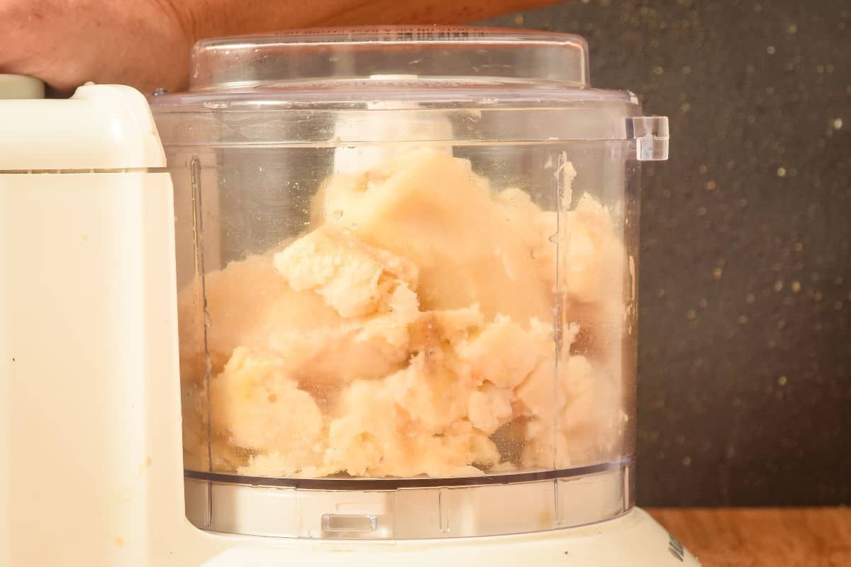 Blending frozen banana chunks in a food processor.