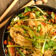 Vegan Pad Thai in a black bowl with chopsticks and peanuts on the side.