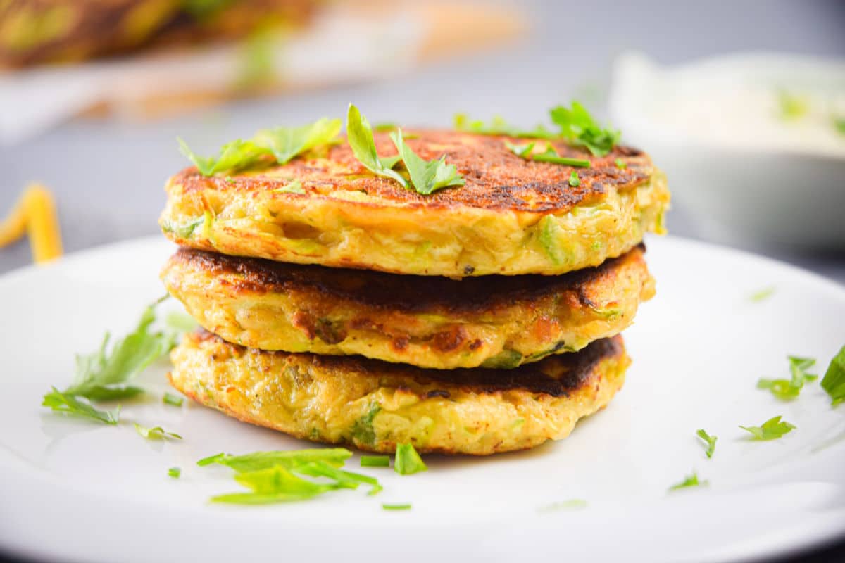 Vegetarian Zucchini Crab Cakes on a white plate with chopped parsley.