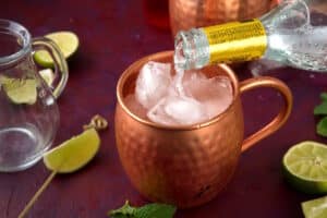 Ginger beer pouring into ice filled Moscow Mule mug.