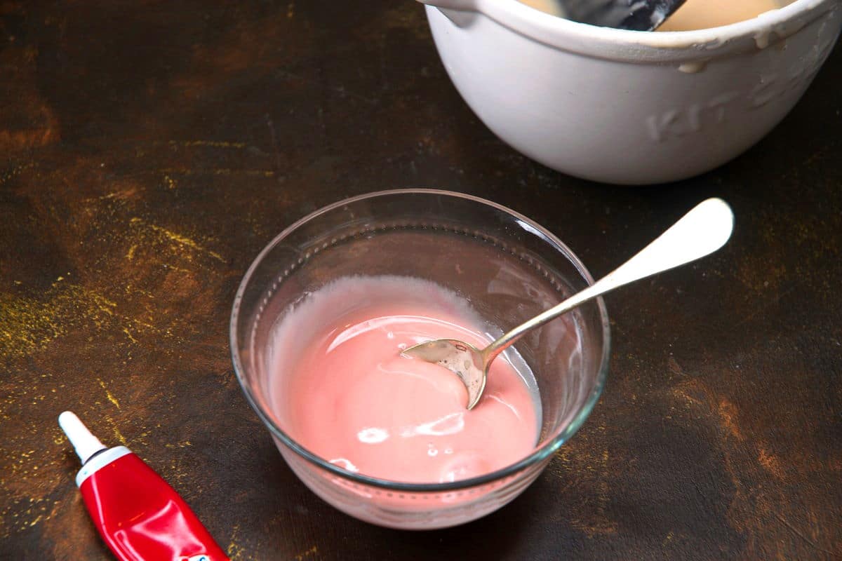 Cake pop icing/glaze in bowl with red food coloring.