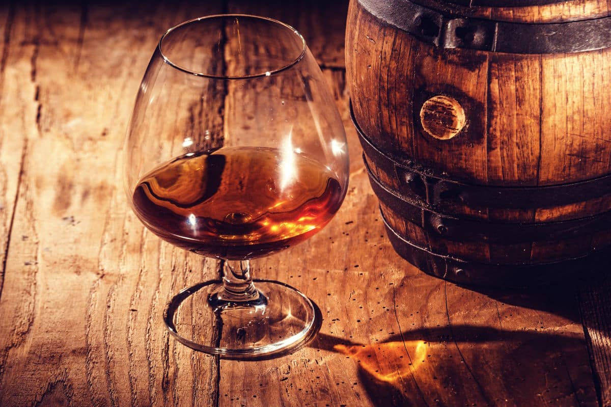 Aged rum on a wooden table and a barrel.