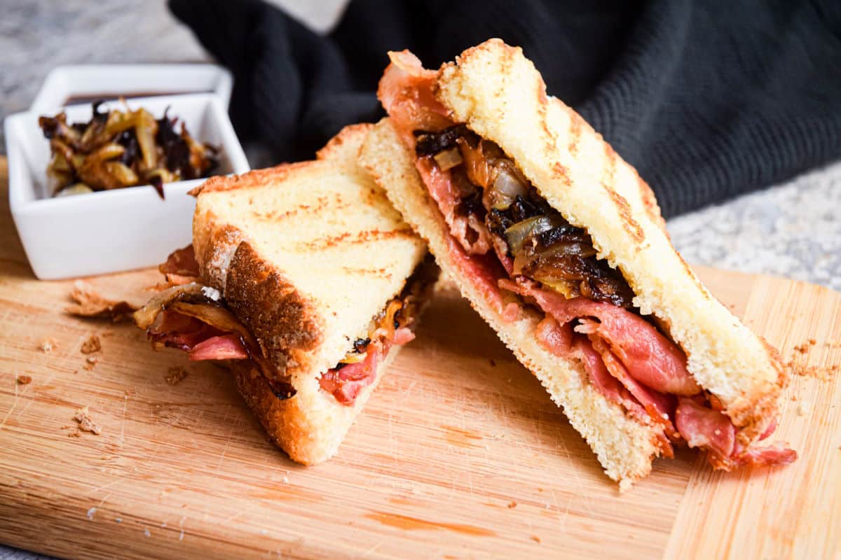 Bacon sandwich sliced in half on cutting board.