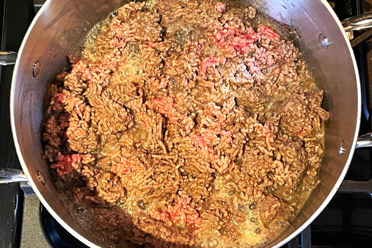 Ground beef cooking in Dutch oven pot.