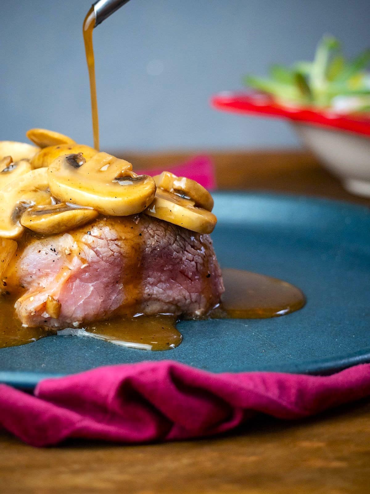 Mushroom sauce drizzling onto beef tenderloin.