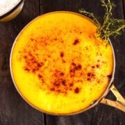 Beer cheese dip in saucepan with paprika and thyme.