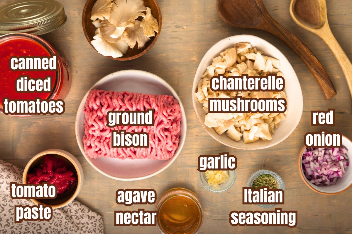 Bison chanterelle meat sauce ingredients prepped and labeled on brown background.
