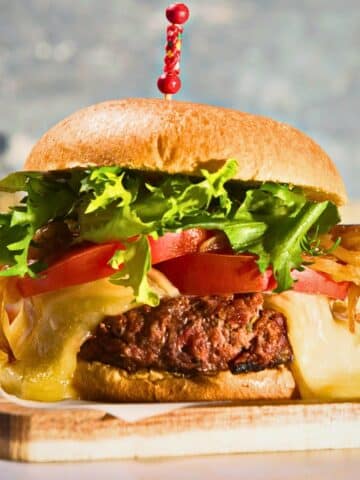 Bison burger with toothpick on cutting board.