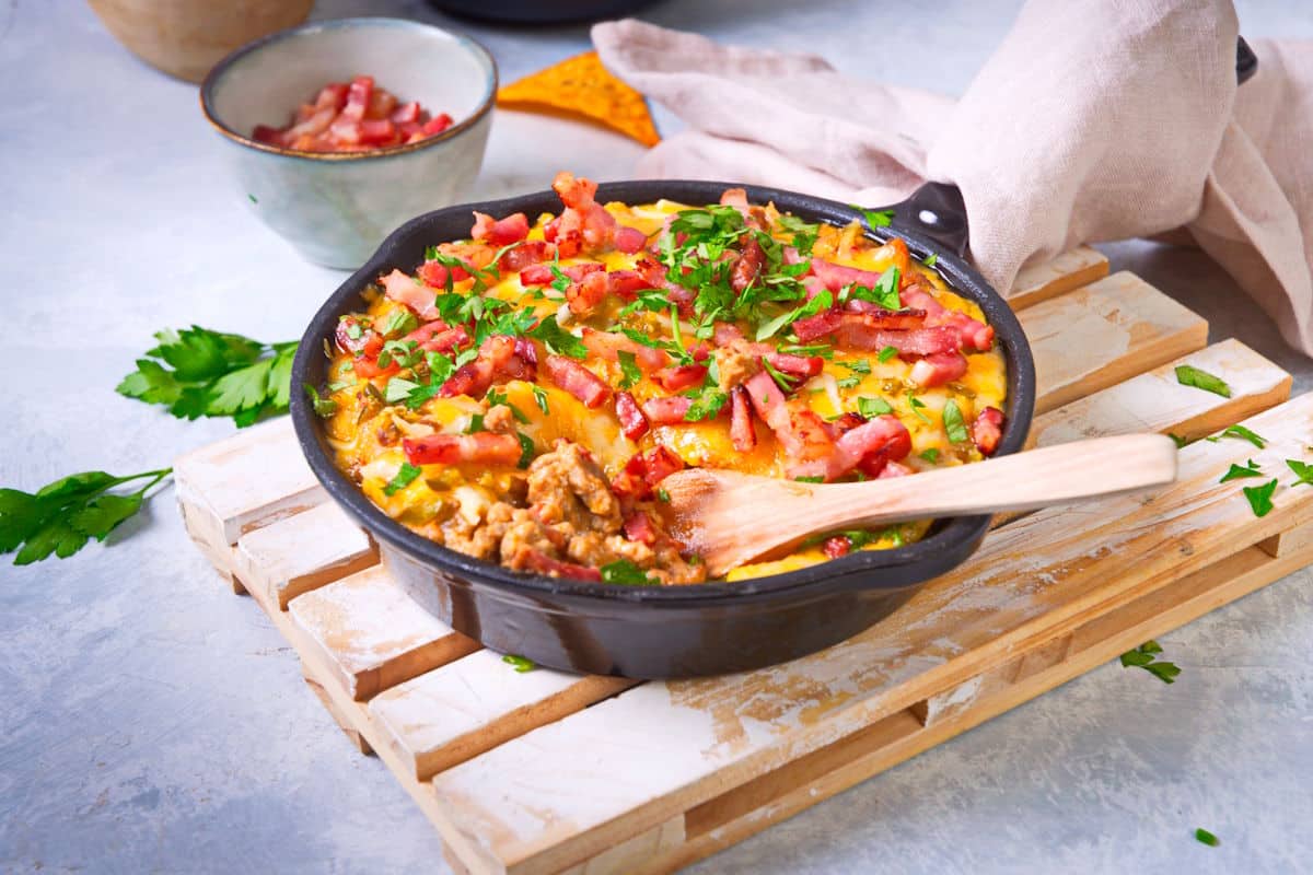 Bison cheeseburger dip in a cast iron pan with wooden spon.