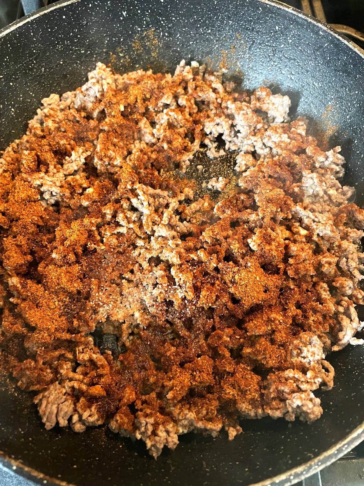 Ground bison and Mexican spices in pan.