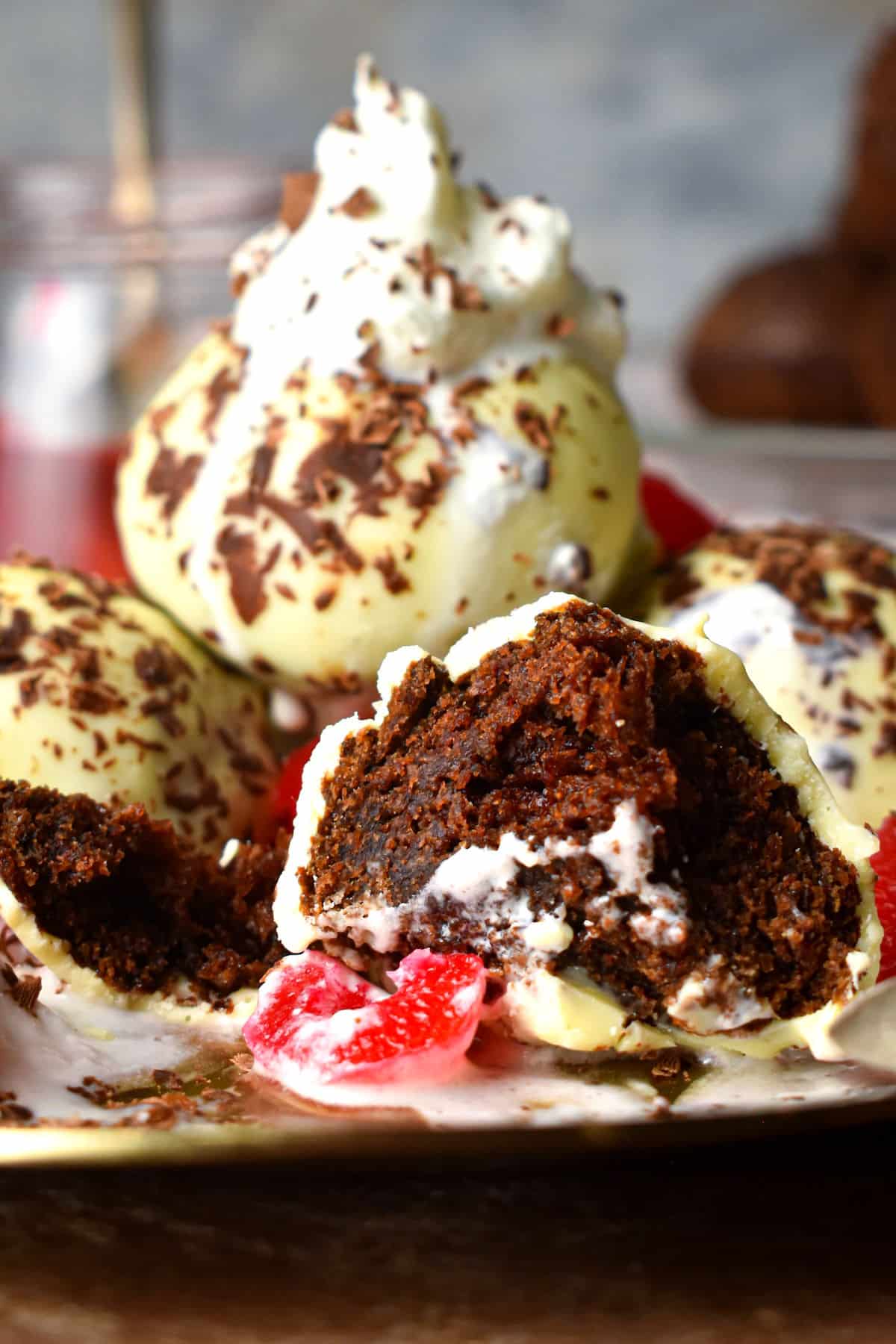 Black Forest cake balls stacked on plate, cut open with whipped cream.