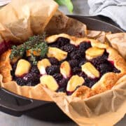 Blackberry galette with brie cheese and thyme in cast iron pan.