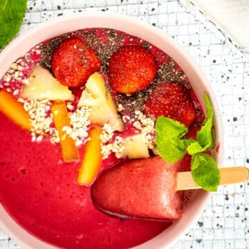 Blackberry smoothie bowl with fruit and seed toppings and a watermelon popsicle.