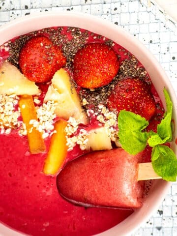 Blackberry smoothie bowl with fruit and seed toppings and a watermelon popsicle.