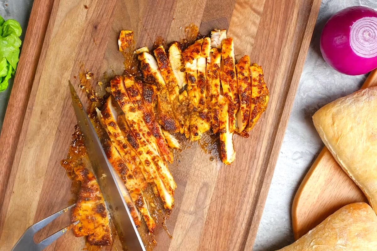 Blackened chicken breast sliced on cutting board.
