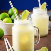 Brazilian lemonade in glasses with straws and lime wedges.