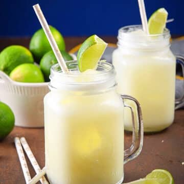 Brazilian lemonade in glasses with straws and lime wedges.