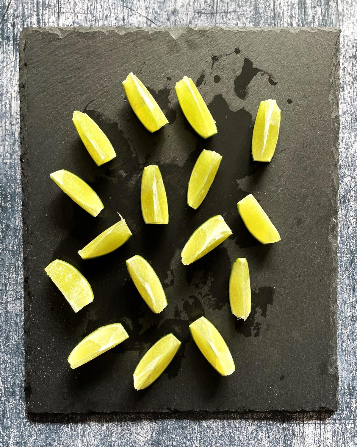 Lime wedges on black cutting board.