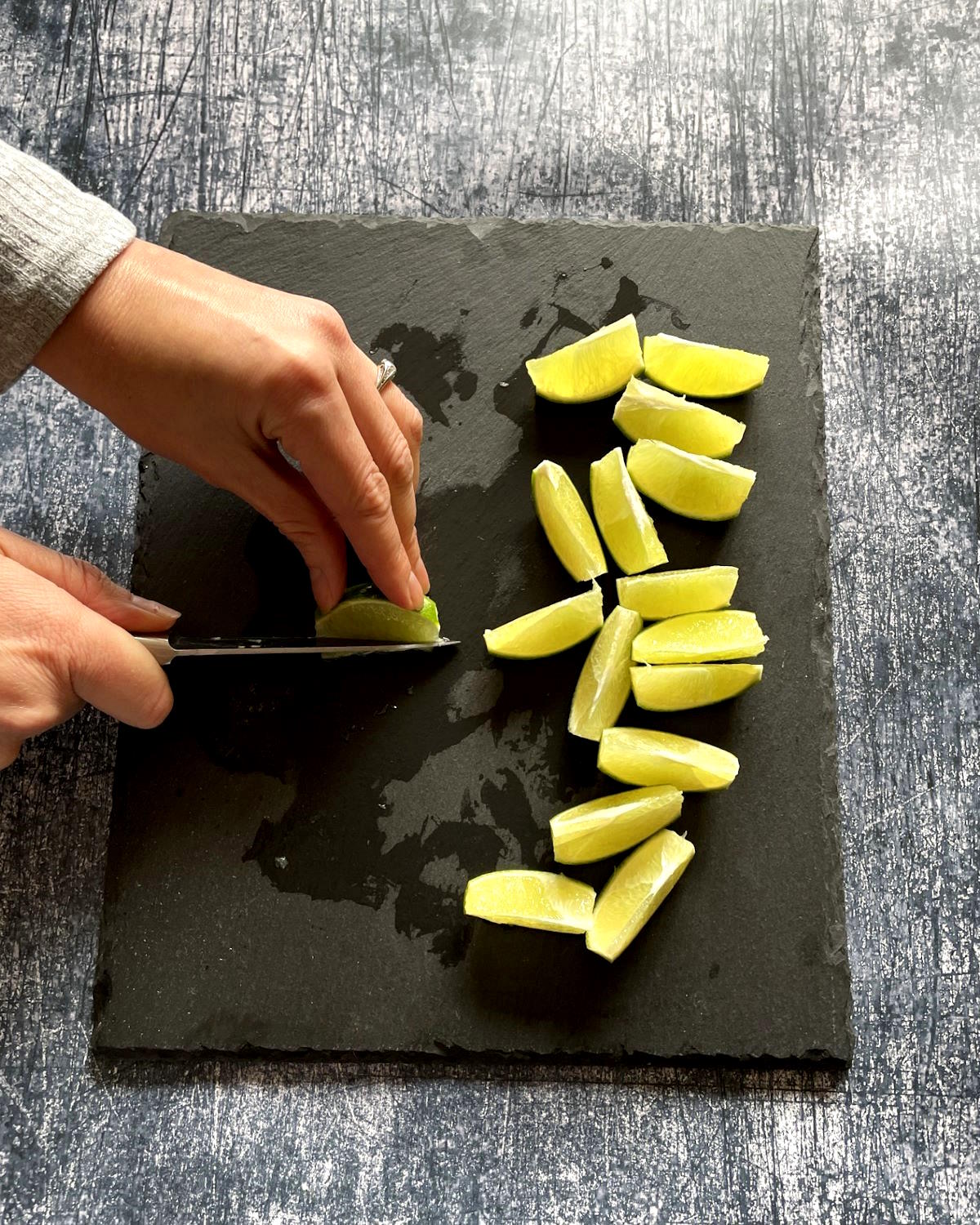 Woman's hands cutting pith off of lime wedges.