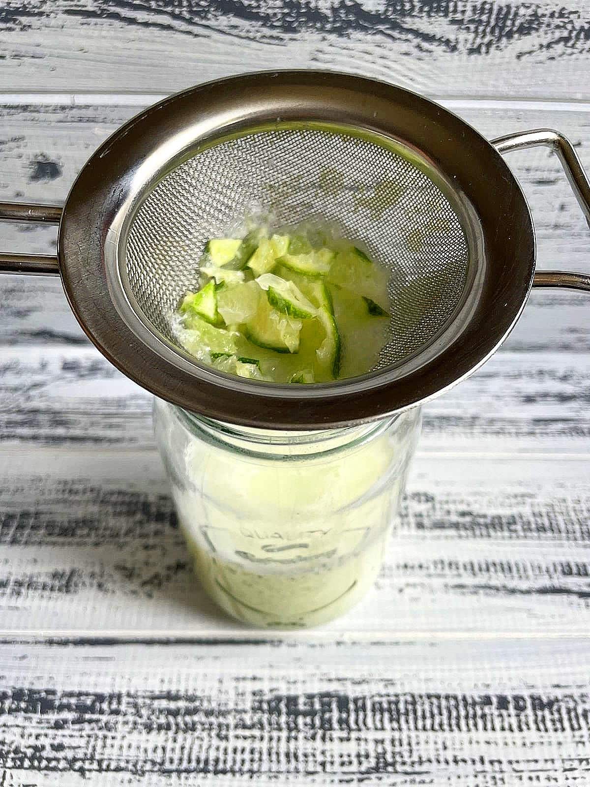 Strainer with lime pieces over top of glass with Brazilian lemonade.