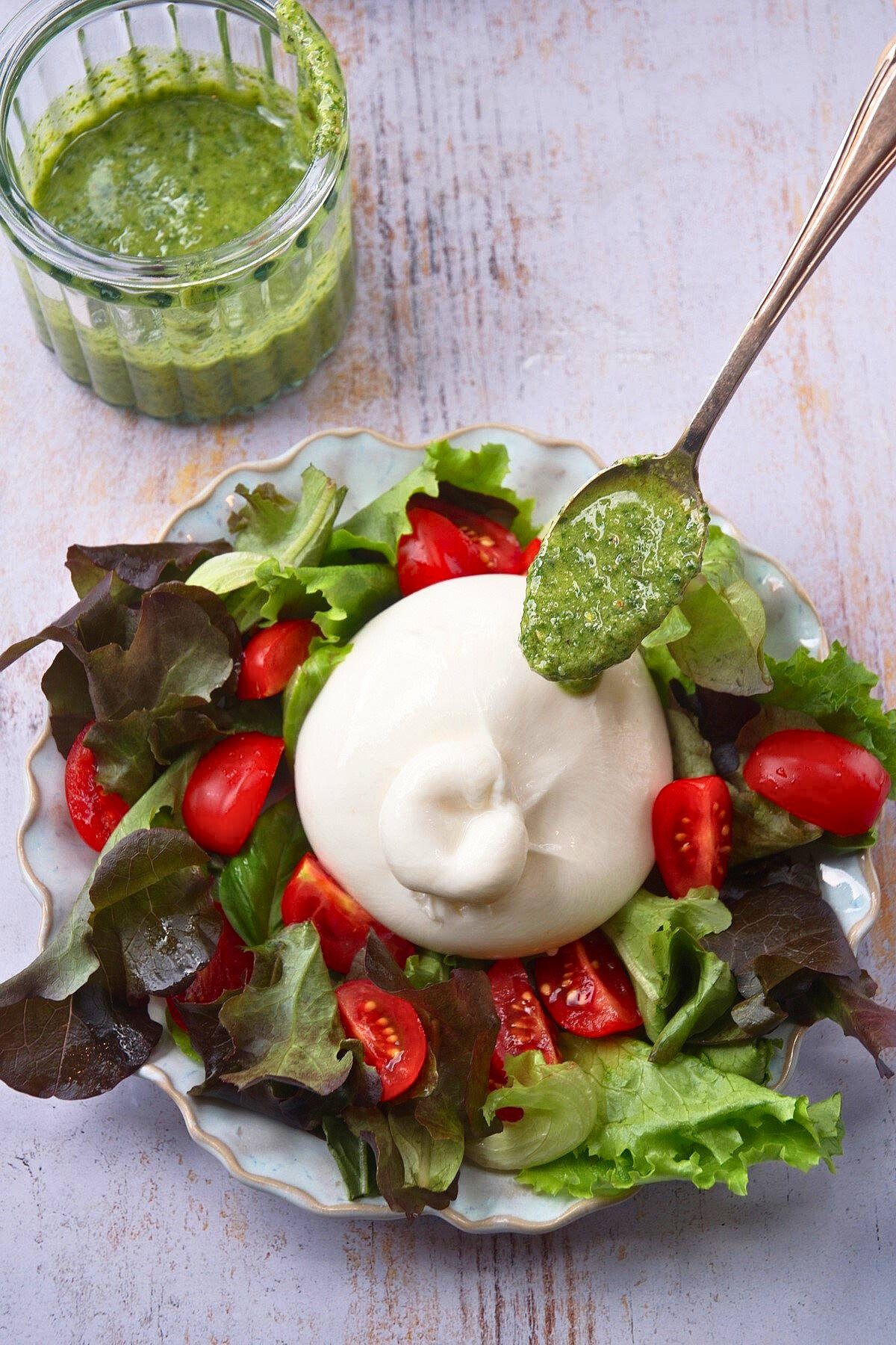 Burrata salad with spoonful of pesto.