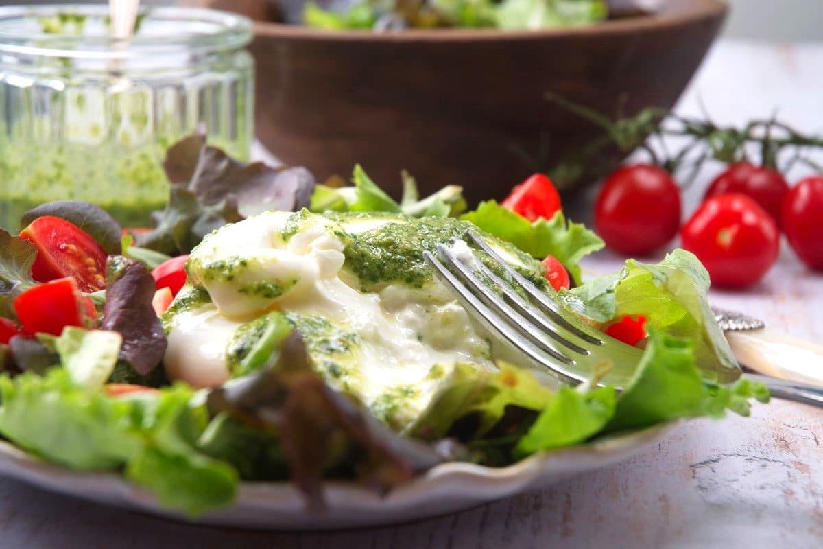 Burrata salad with the cheese cut open with a fork.