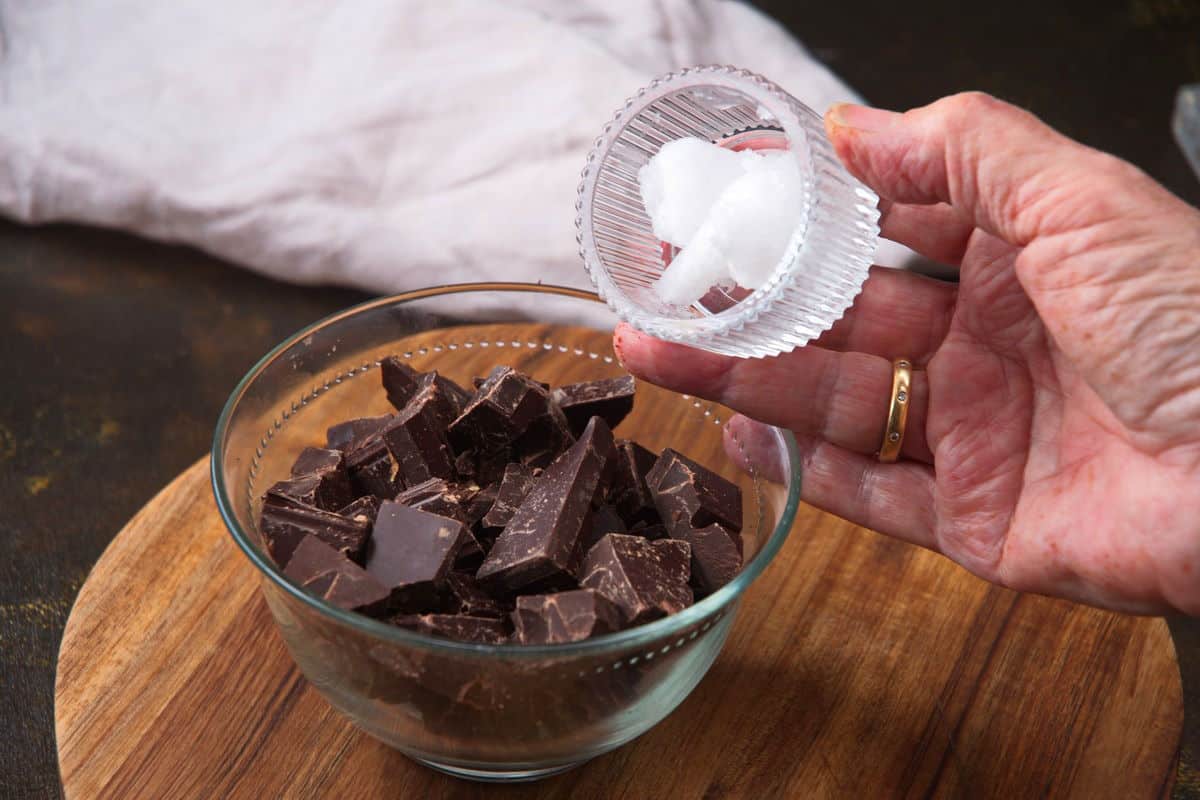Chocolate bar chunks in a small bowl and coconut oil.