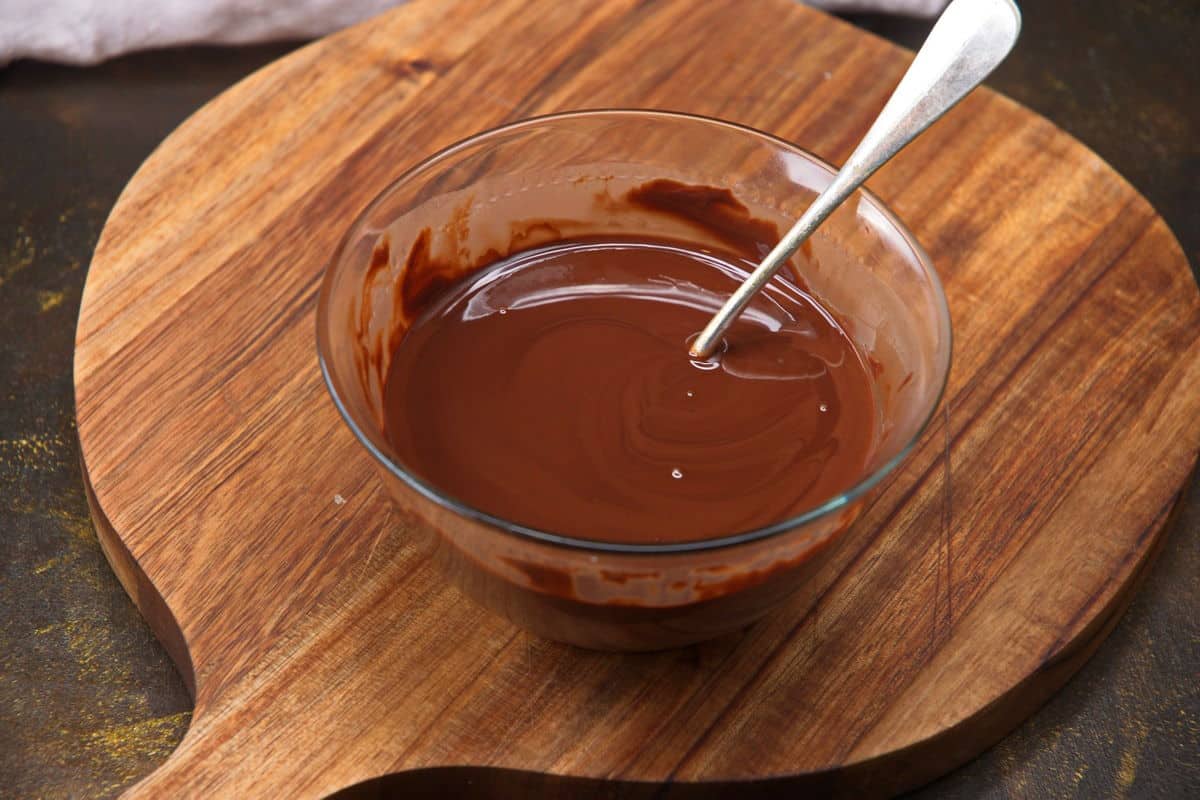 Chocolate and coconut oil mixture in small bowl with spoon, melted.