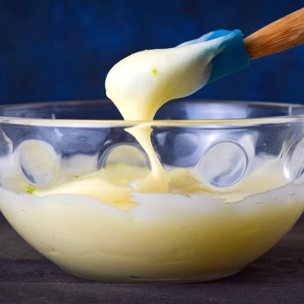 Cake pop frosting in bowl with spatula.
