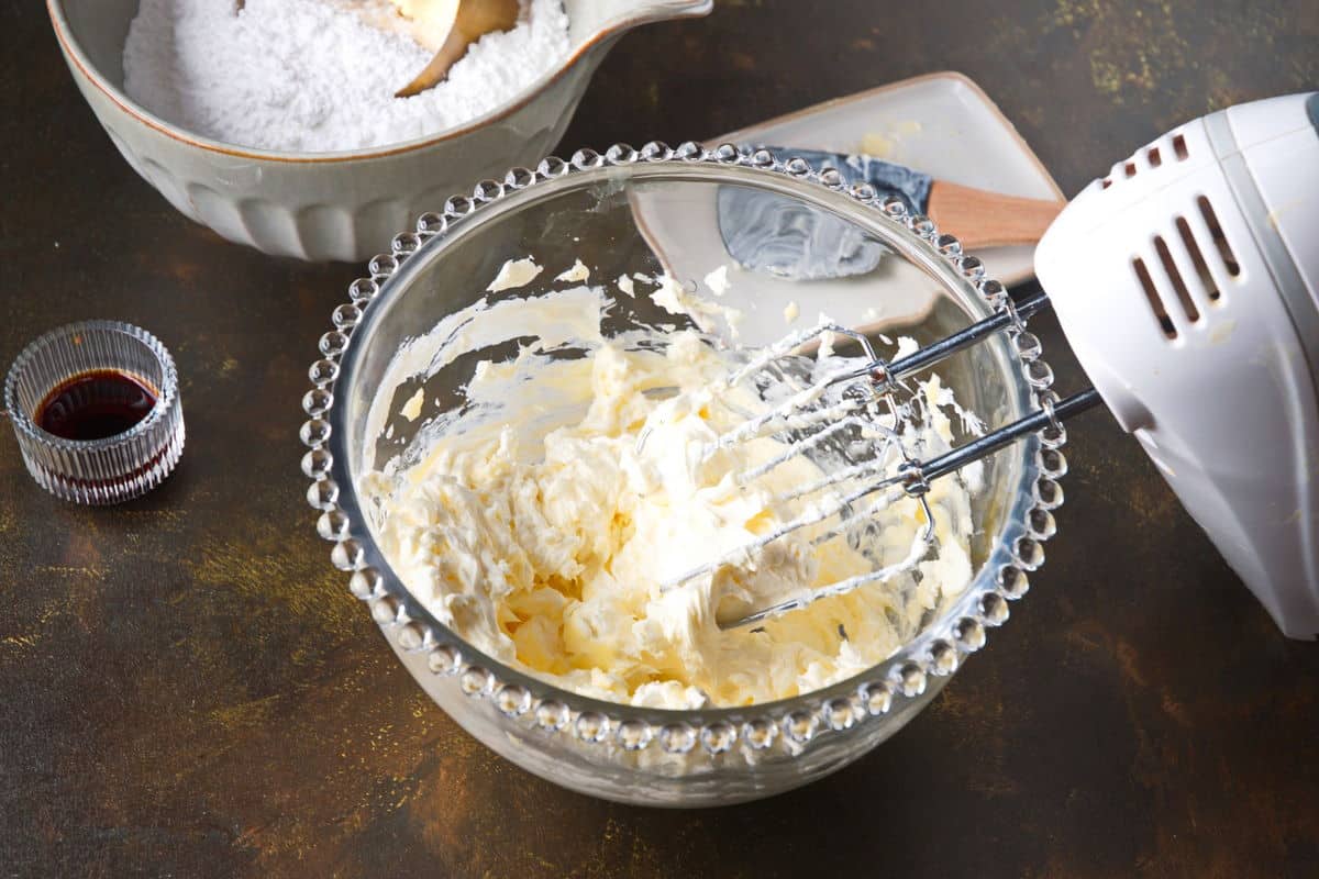 Cream cheese and butter in bowl with electric mixer.