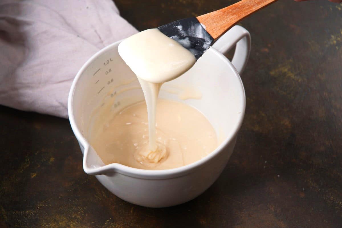 Cake pop icing in bowl and running down spatula.