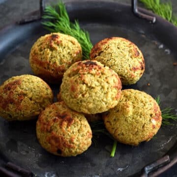Falafel on black plate with fresh dill.