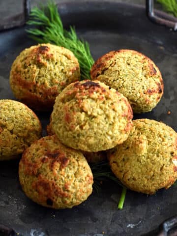 Falafel on black plate with fresh dill.