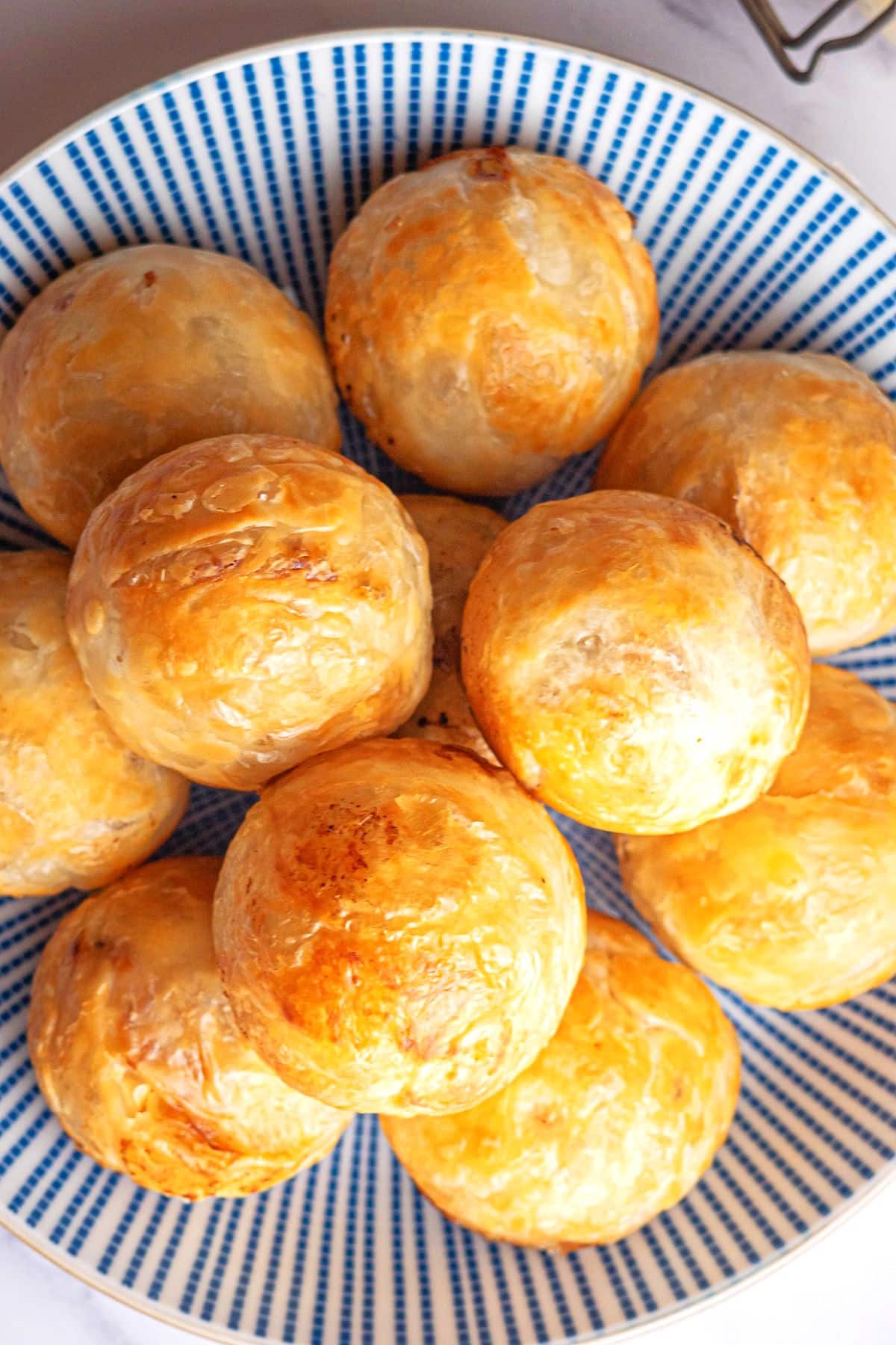 Puff pastry chicken balls arranged on blue and white plate.