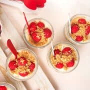 Canada Day raspberry cheesecake in jars with red and white spoons.