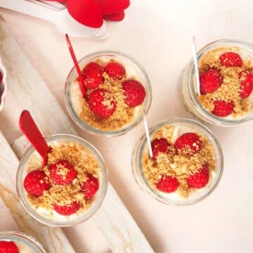Canada Day raspberry cheesecake in jars with red and white spoons.