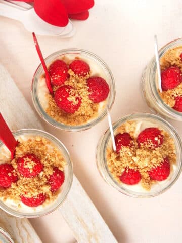 Canada Day raspberry cheesecake in jars with red and white spoons.