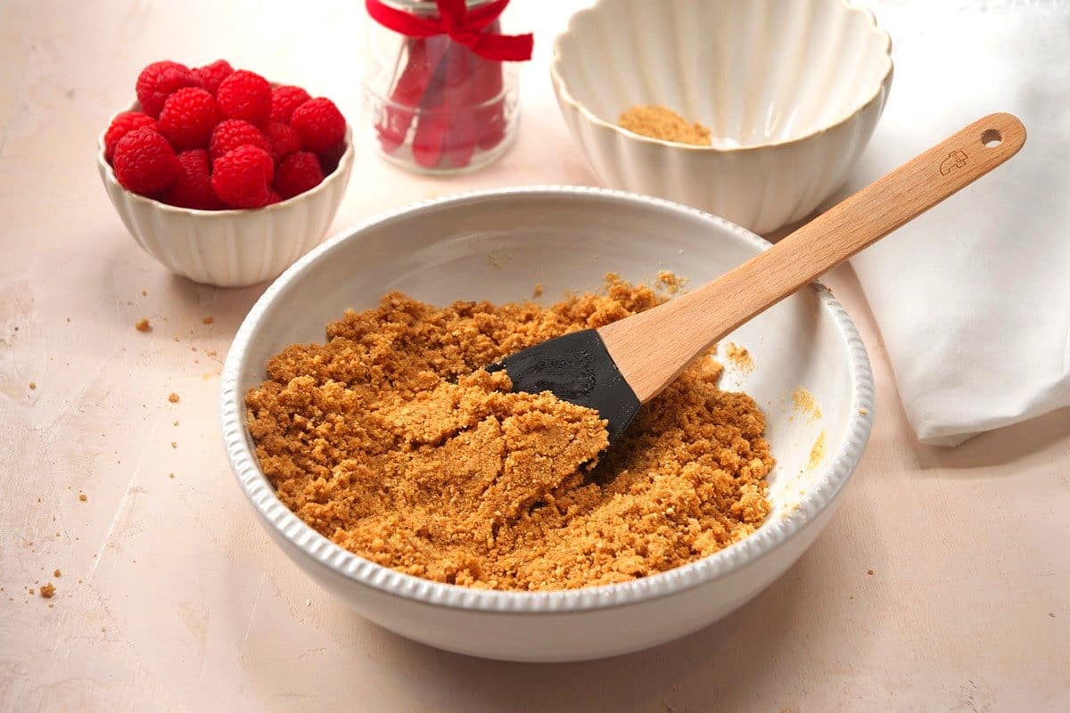 Graham cracker crumbs mixed with butter in small bowl.