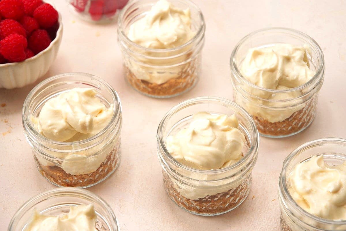 Graham crackers crumbs and cheesecake mixture in jars.