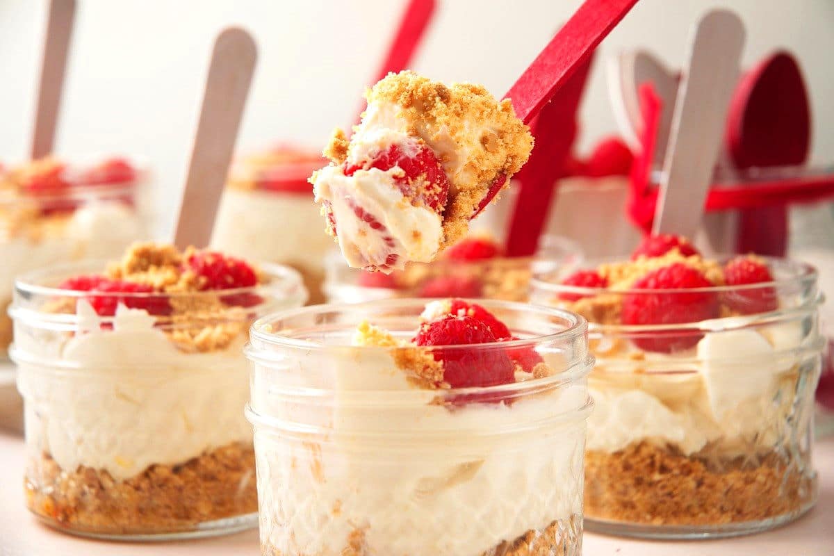 Raspberry cheesecake in a jar with a spoonful of cheesecake.