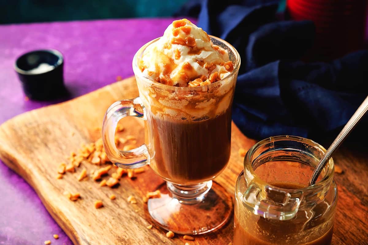 caramel brûlée latte in mug with whipped topping, toffee bits and caramel sauce.