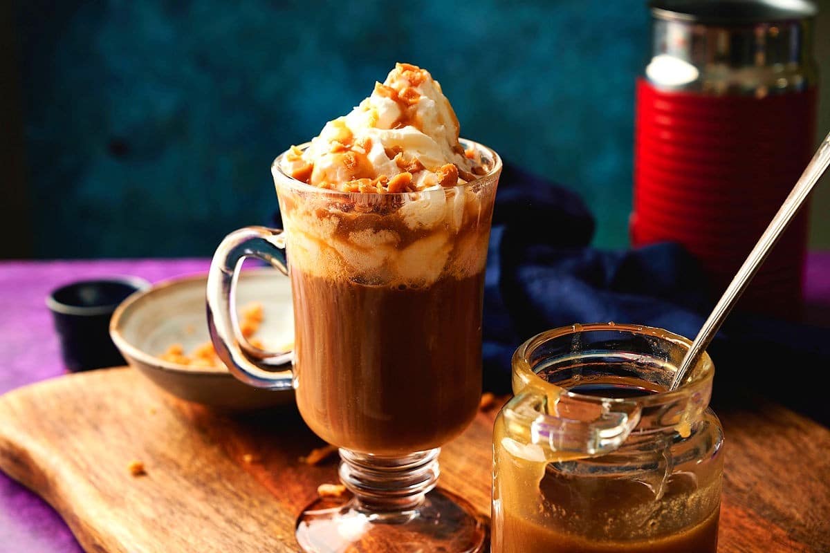 Caramel brûlée latte with jar of caramel brûlée sauce on the side.