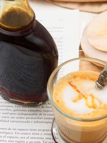 Caramel syrup in a jar and hot coffee in a mug.
