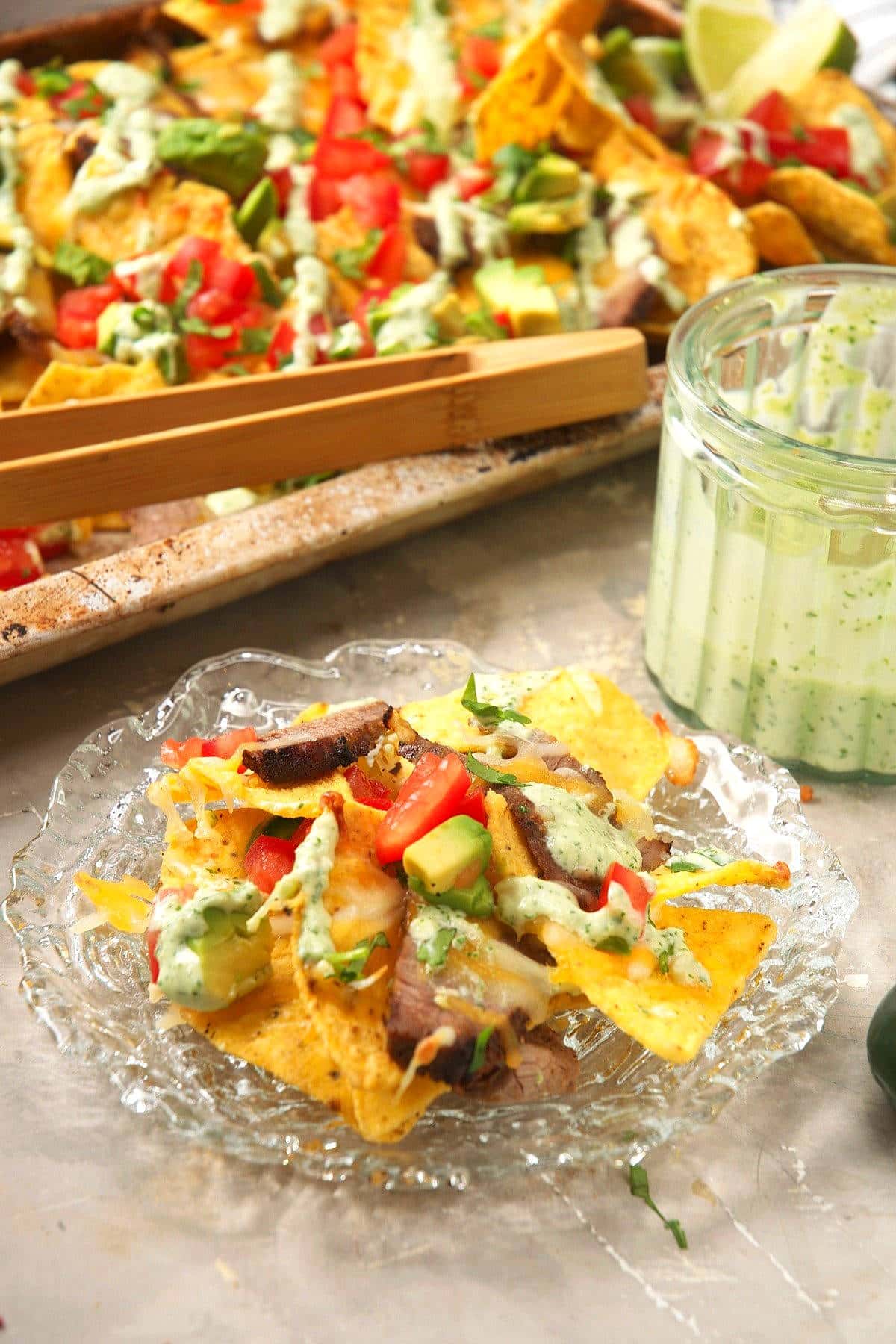 Carne asada nachos on a plate with cilantro dip.