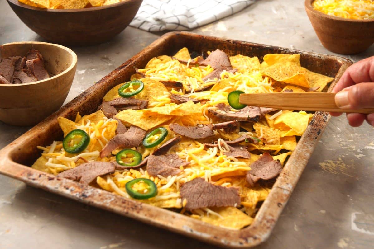 Carne asada nachos assembled on sheet pan.