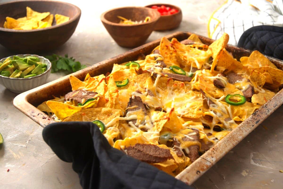 Carne asada nachos baked on sheet pan.